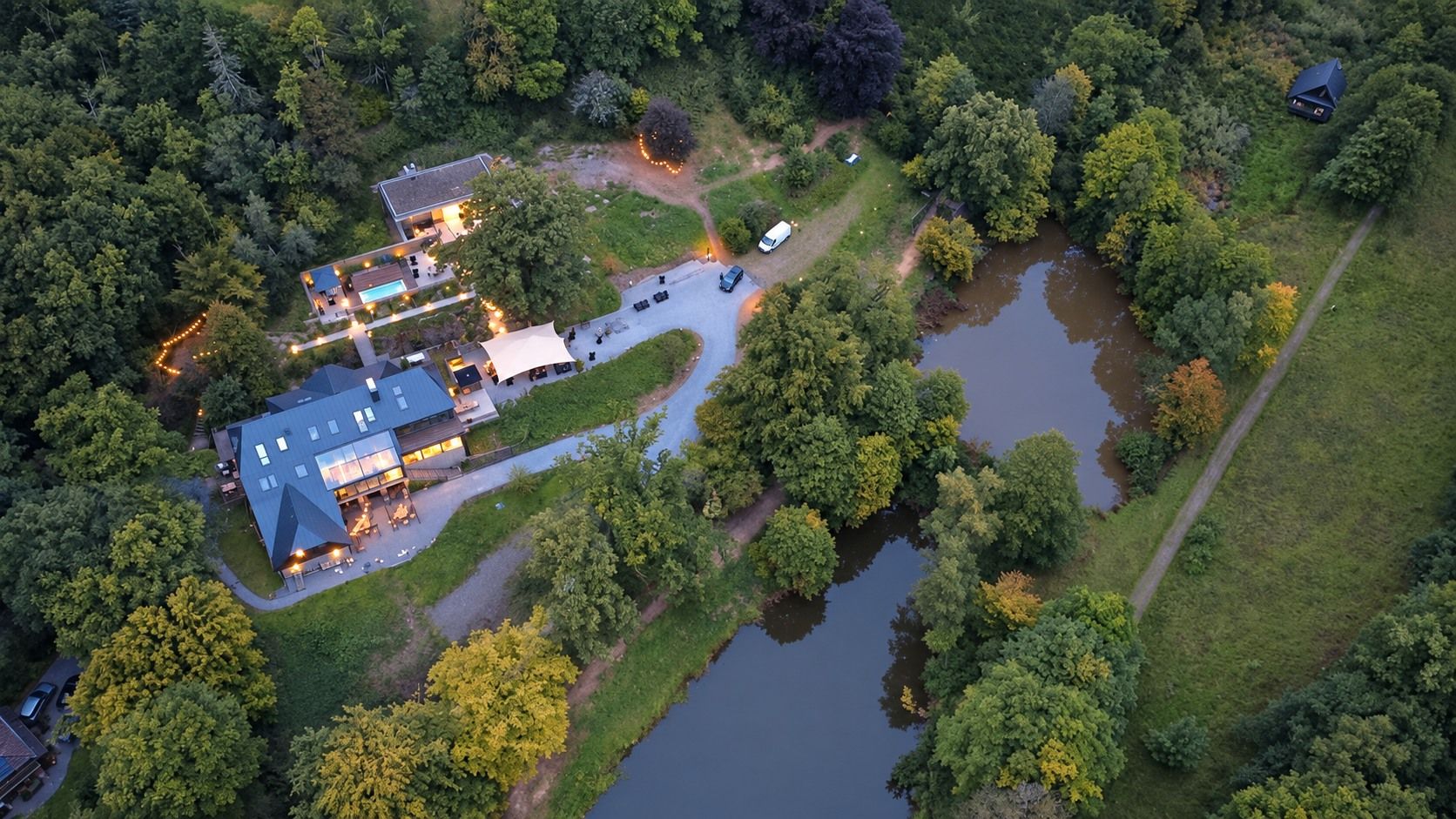 Luftaufnahme des Homestorys Nature Resorts mit Gebäuden, Teichen und weitläufiger Waldlandschaft in Eupen.
